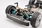 Close-up of a model car chassis with visible suspension and wheels on a white background