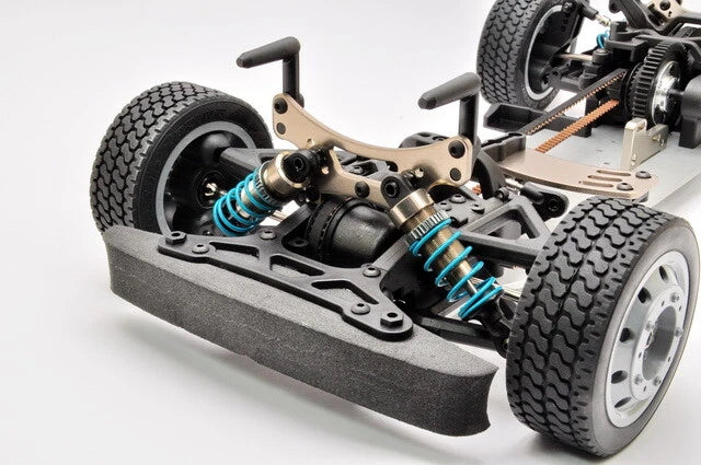 Close-up of a model car chassis with visible suspension and wheels on a white background