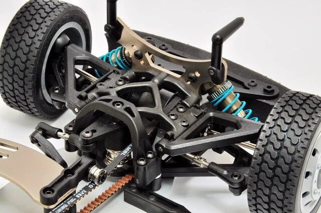Close-up of a detailed model car chassis with suspension and wheels on a white background