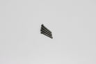 A set of four metal screw pins laid out against a light background.